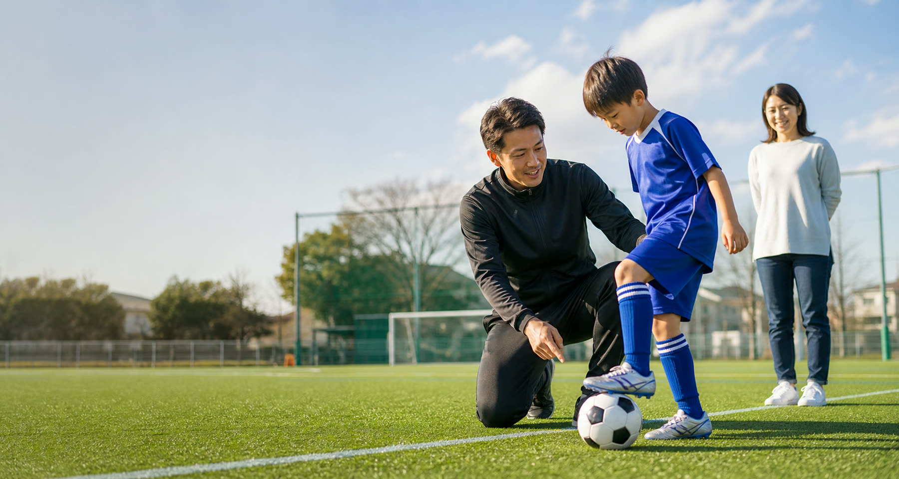 サッカーコーチが子どもと保護者に練習目的を説明している様子